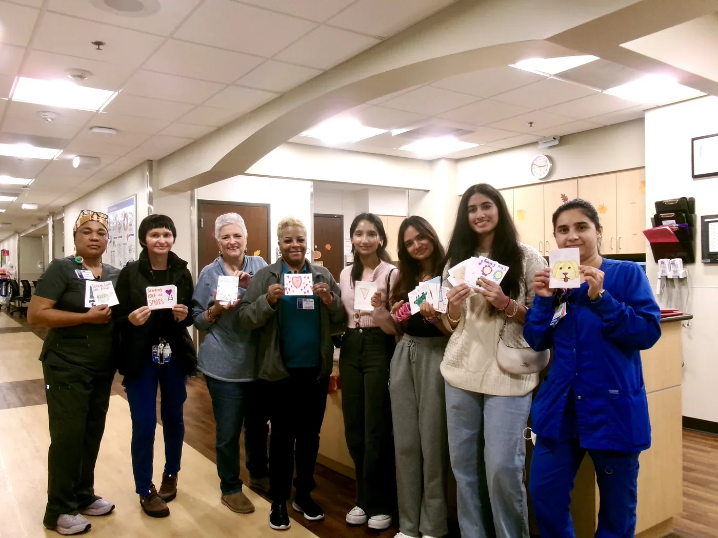 Volunteers and hospital staff in a hallway holding the handmade cards before delivery.
