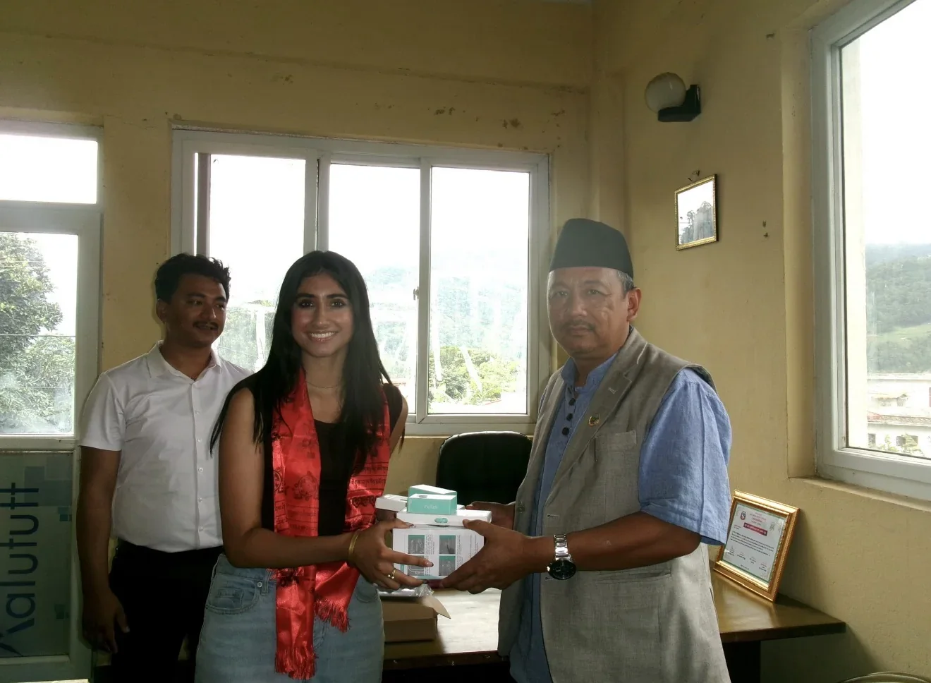 A Heart to Heart volunteer handing a boxed equipment donation to an official in Nepal.