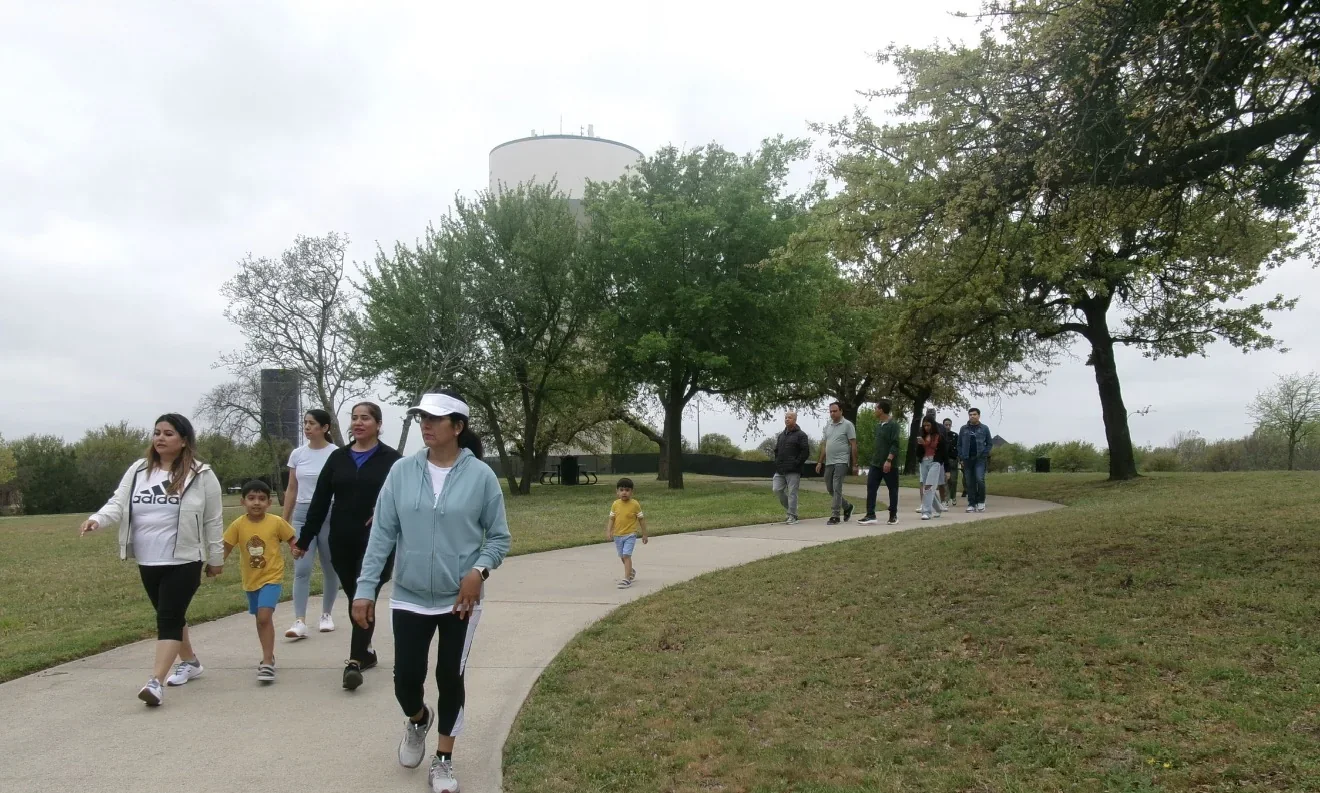Families and students walking a park path at the Heart to Heart Heart Walk.